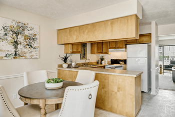 A kitchen with a table and chairs in front of it.